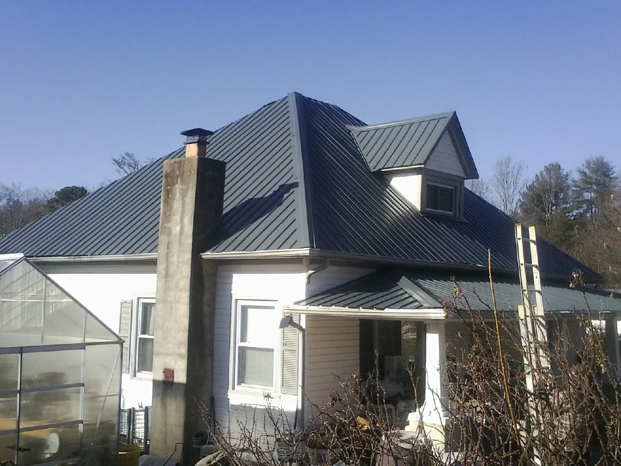 Dark blue standing seam metal roof on a white farmhouse with dormer — Slate & Tile Roof Repair by Roofing Brothers in Peterboro
