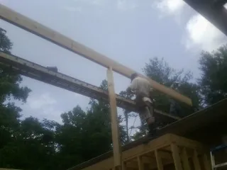 Carpenter setting a ridge beam over a new addition frame — Ice Dam Removal by Roofing Brothers in Peterboro