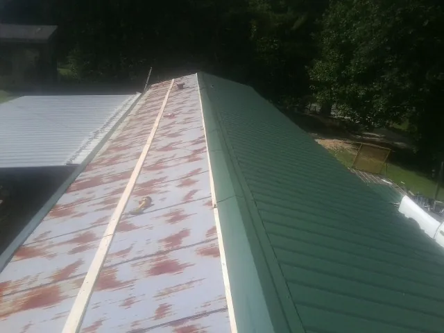 Old rusted panels beside newly installed green metal roofing — Wind Damage Roof Repair by Roofing Brothers in Peterboro