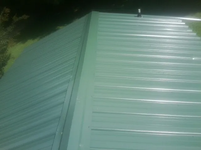 New green metal panels meeting at the ridge of a roof — Flat Roof Repair work by our crew in Peterboro