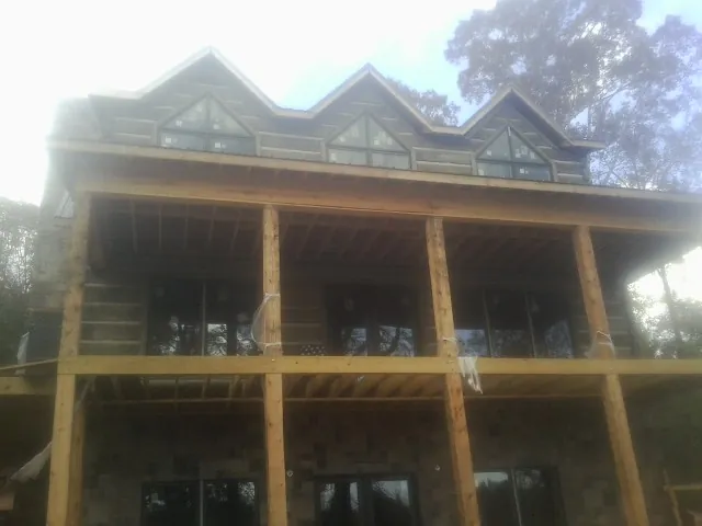 Dormers and porch framing on a large log home under construction — Roof Coating work by our crew in Peterboro