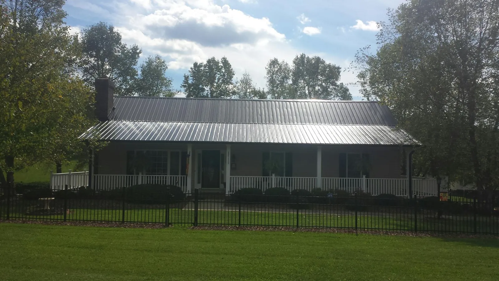 Gray metal roof on a brick ranch with a full width front porch — Gutter Guard Installation work by our crew in Peterboro