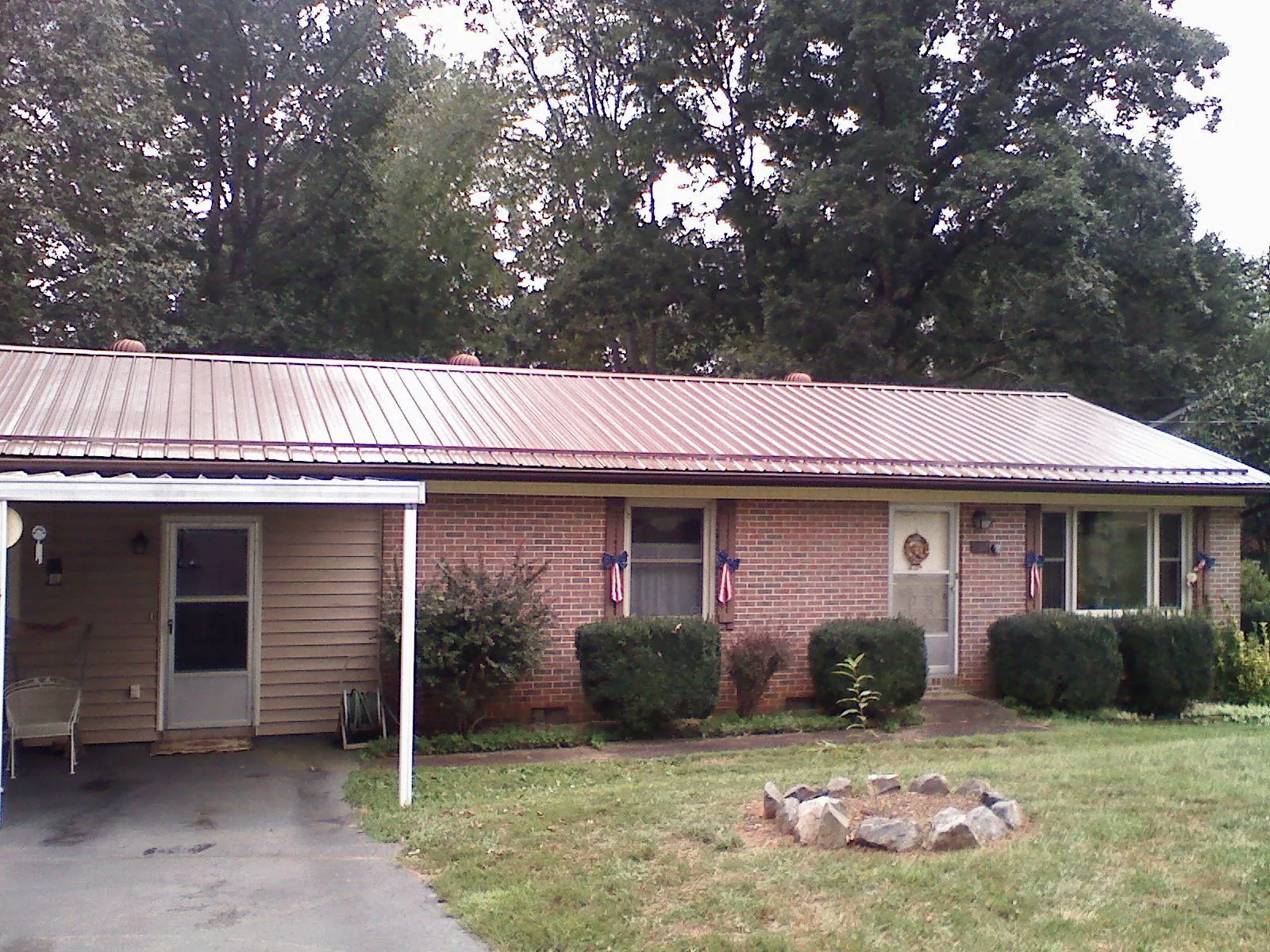 Bronze metal roof and carport on a brick ranch home — Roof Repair work by our crew in Peterboro