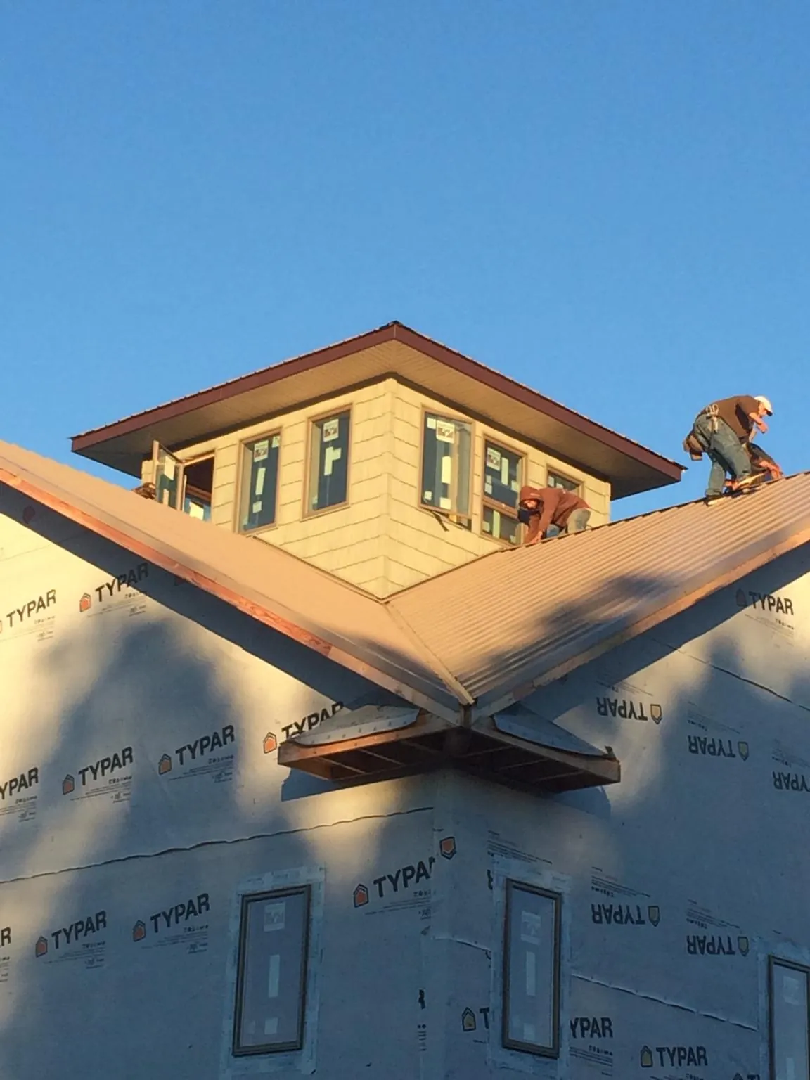 Roofers working around a rooftop cupola on a new metal roof at sunset — Roof Waterproofing in Peterboro by Roofing Brothers